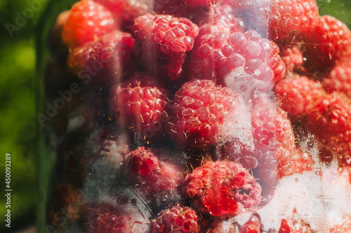 Ripe red, fresh, tasty and sweet raspberries in a large glass jar. Fruit from the garden.