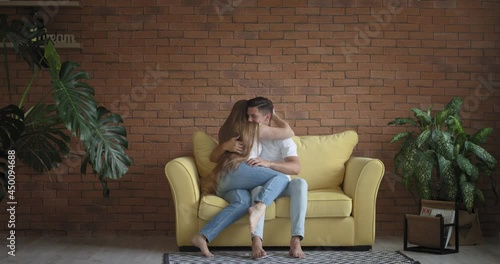 Handsome young man and two beautiful women hugging on sofa. Polyamory concept photo