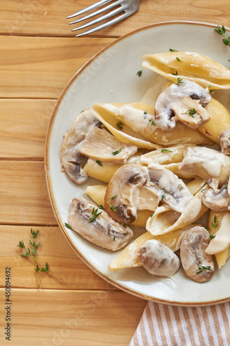 Creamy pasta with mushrooms and thyme. Top view, wooden background.