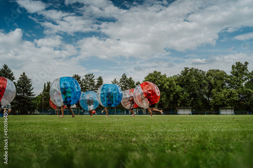 People playing in Bubble Football. Zorbing bumper football soccer on a green field