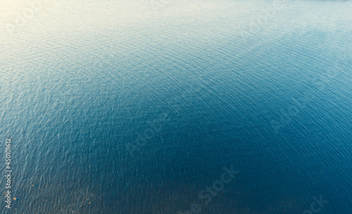 Aerial view of a crystal clear sea water texture. Top view from above. Natural blue background. Blue water reflection. Blue ocean wave. Summer sea. Drone. Top view