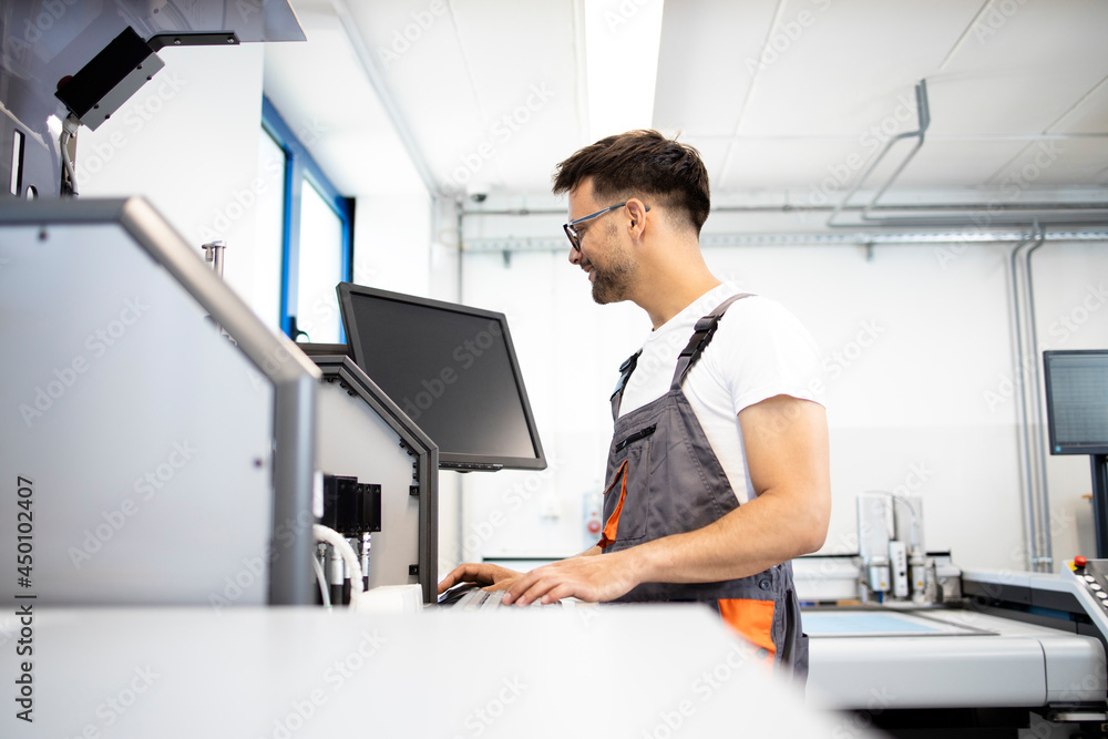 Fototapeta premium Worker operating industrial machine in automated factory.