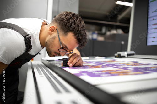Photo Worker checking print quality of graphics in modern printing house