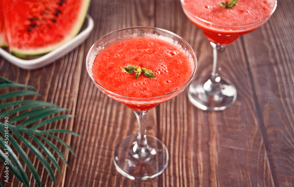Watermelon refreshing summer frozen cocktail smoothie with watermelon slices and pieces on the background