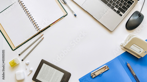 Layout on the topic of working process or education on a white background with notepad, pen, laptop, computer mouse, tablet, hole punch, headphones, pencil