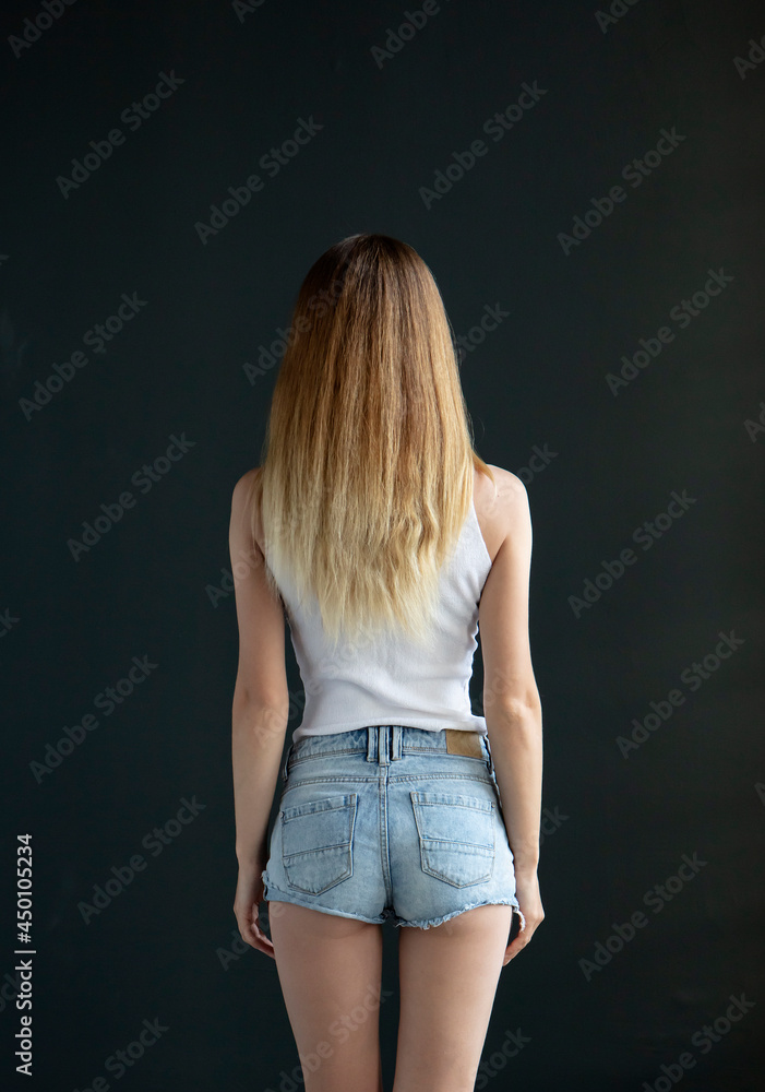 Portrait of a beautiful girl in a T-shirt and shorts in full growth on a black background in the studio. Presenting your product. Fashion Portrait of a beautiful girl in a T-shirt and shorts in full growth on a black background in the studio. Presenting your product. Fashion