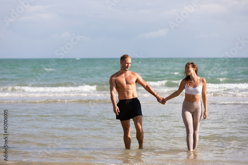 happy couple walking and splashing water on the sea in summer day