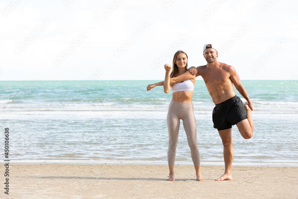 young athletic couple stretching and exercise together on the beach young athletic couple stretching and exercise together on the beach