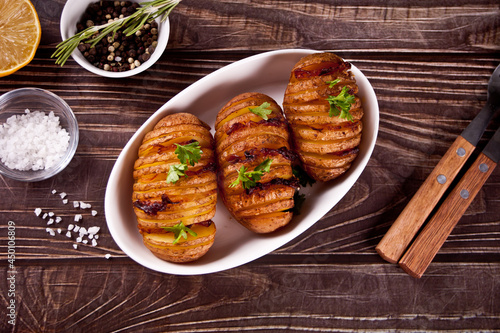 American traditional homemade Hasselback Potato and stuffed potatoes with fresh herbs and bacon.