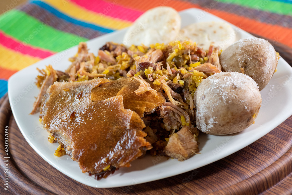 Lechona with potato and arepa on white plate and colorful background. Lechona with potato and arepa on white plate and colorful background.