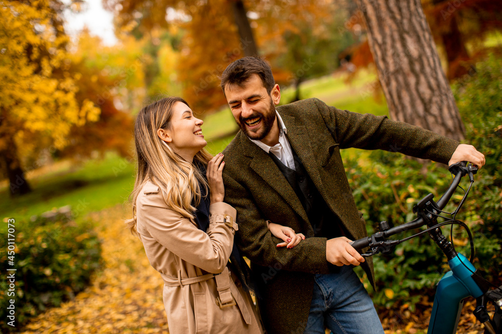 Fototapeta premium Young couple in the autumn park with electrical bicycle