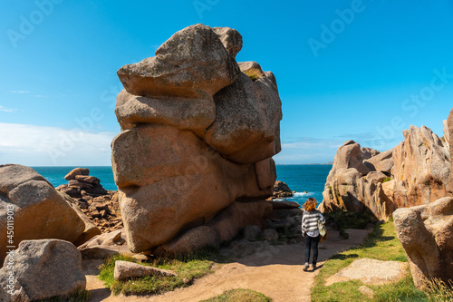 A young woman on a footpath on the coast next to Lighthouse Mean Ruz, port of Ploumanach, in the town of Perros-Guirec, Cotes-d'Armor, in French Brittany, France. photo