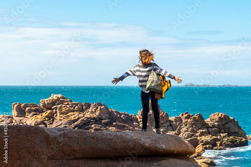 A young woman looking at the sea along Lighthouse Mean Ruz, port of Ploumanach, in the town of Perros-Guirec, Cotes-d'Armor, in French Brittany, France. photo