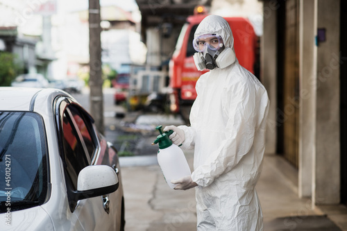 Man in protective suit and mask sprays disinfectant