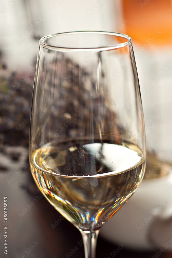 Glass of white wine close up. Alcoholic drink on a wooden table on a background of the city. Transparent wine on the summer terrace of the restaurant.