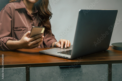 Young woman working from home with laptop computer and smartphone