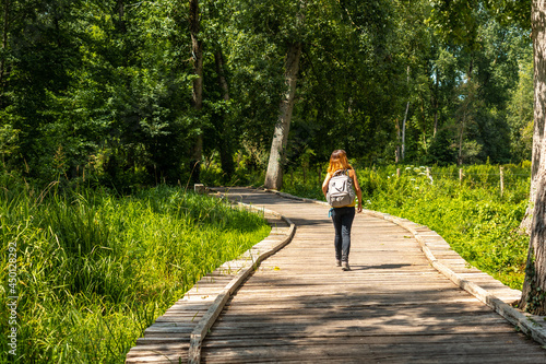 A young woman on the footpath along a footbridge between La Garette and Coulon, Marais Poitevin the Green Venice, near the town of Niort, France © unai