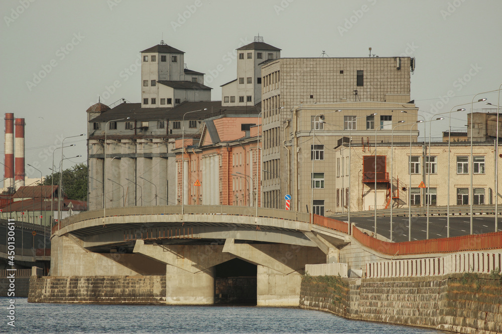 Urban landscape: modern bridge and old factory on the river bank