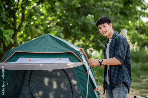 Canvas Print young man spreading a tent flysheet for camping trip.