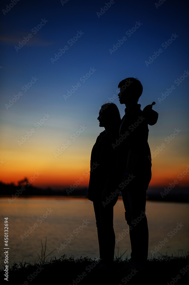 silhouette of young couple standing near the lake