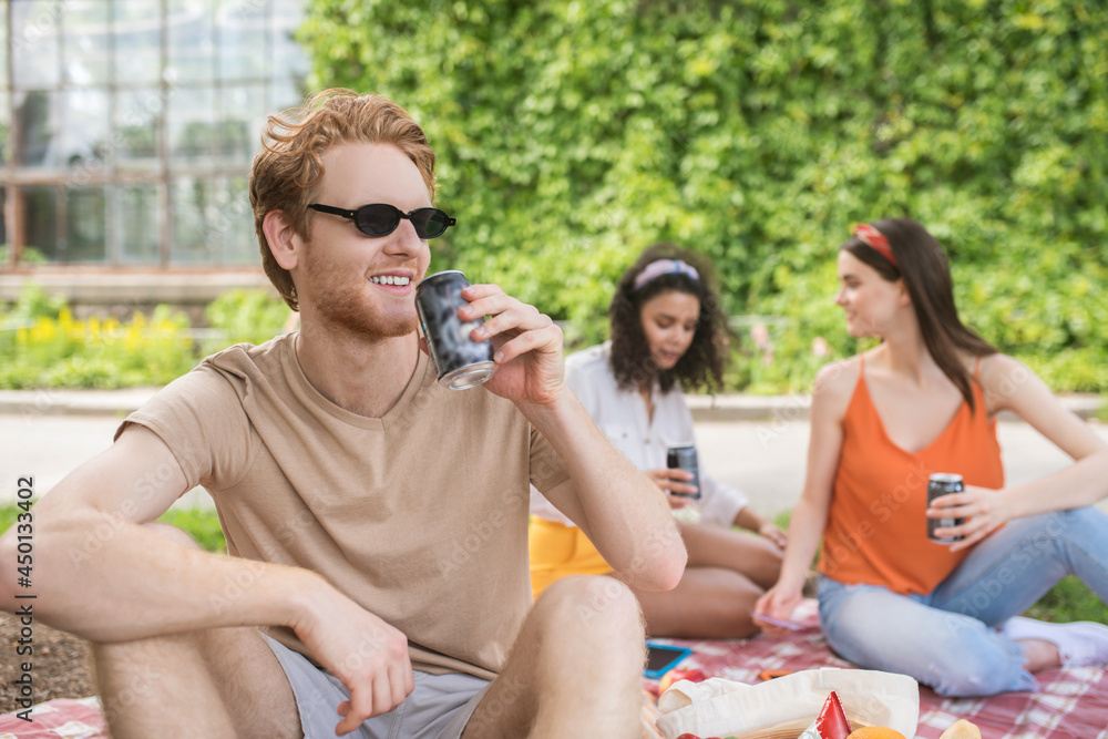 Friendly guy in sunglasses with drink and girlfriends Friendly guy in sunglasses with drink and girlfriends