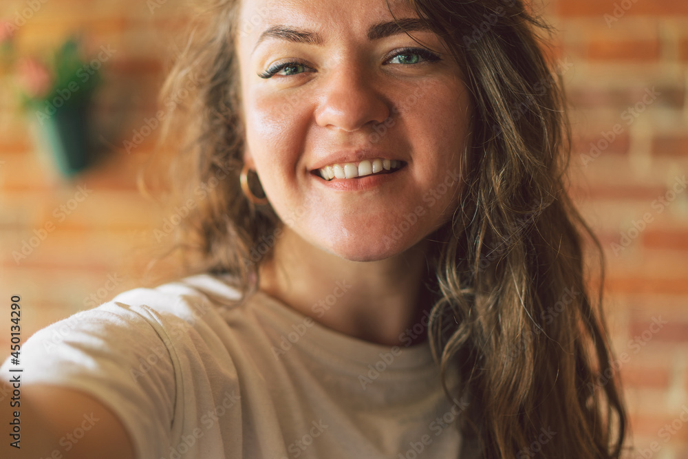 Young woman smiling and looking in camera and takes a selfie. Lifestyle concept Young woman smiling and looking in camera and takes a selfie. Lifestyle concept