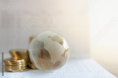 Global Business, Money and Financial Concept. Closeup of glass world ball with stack of gold coins on bank passbook with copy space.