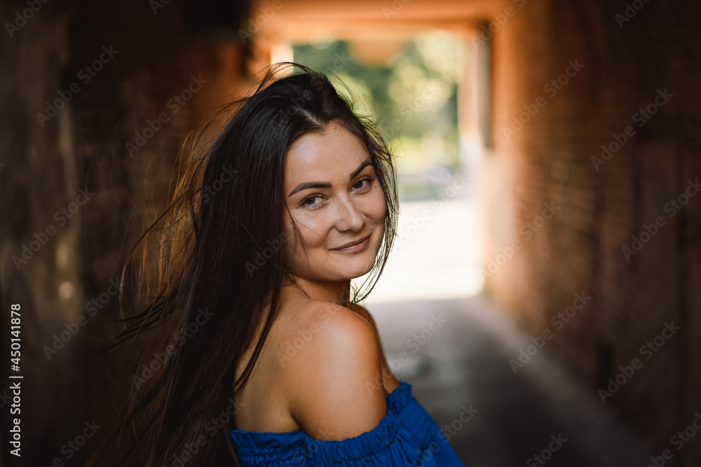 Fototapeta premium Portrait happy young woman wearing blue dress laughing looking at camera standing on street. Urban background