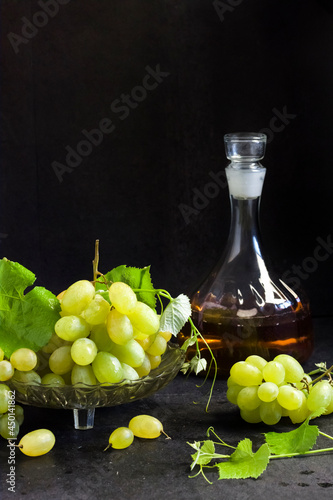 Fresh ripe grapes and decanter with grape juice on black background