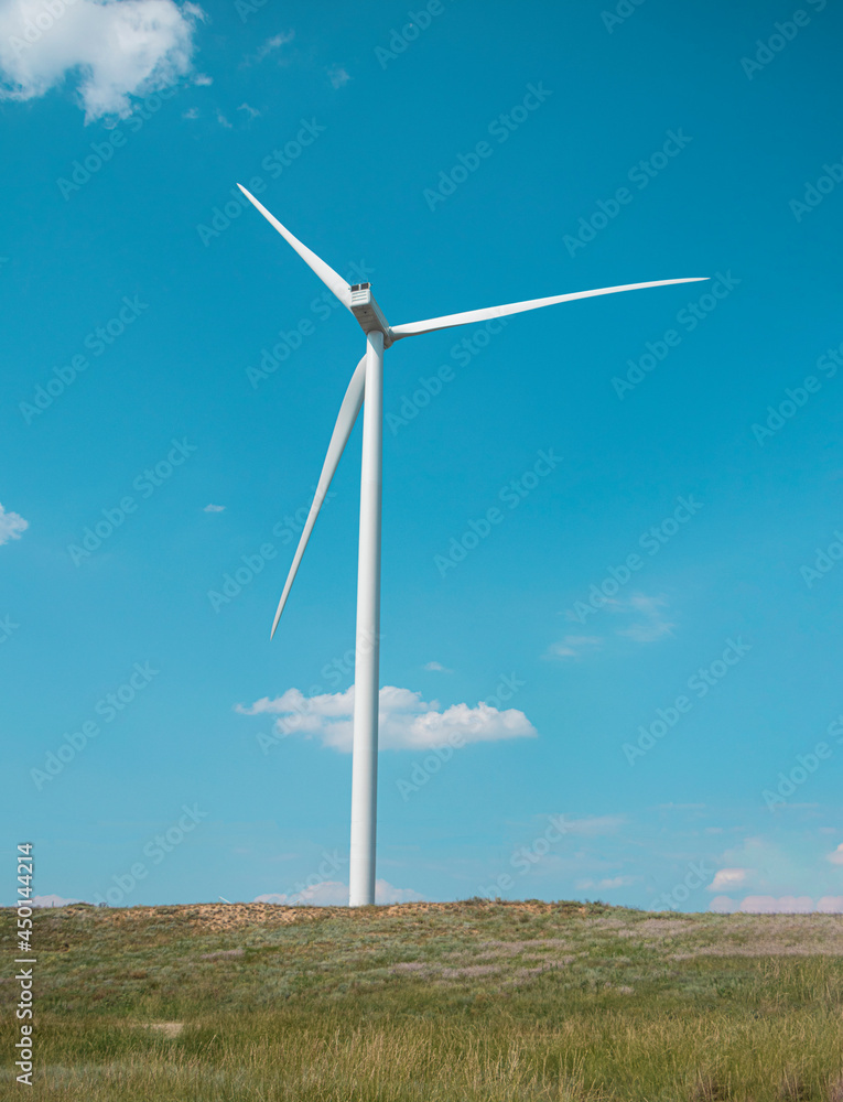 windmill on the background of the cloudy blue sky. Concept of alternative energy production from wind. Modern windmill with full-length blades. High quality photo windmill on the background of the cloudy blue sky. Concept of alternative energy production from wind. Modern windmill with full-length blades. High quality photo