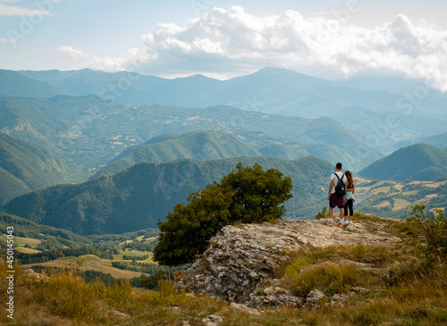 Couple of young people, boy and girl, hugging each other looking at the view from the mountain © Marco Bonomo