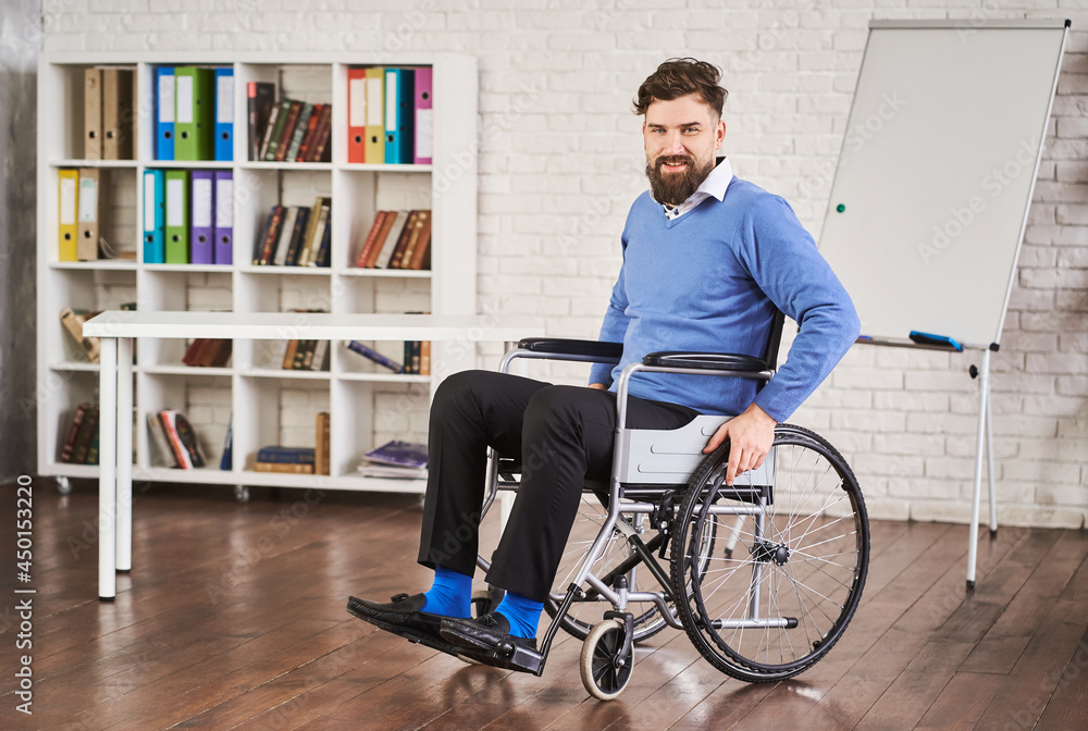 Smiling disabled businessman sitting in a wheelchair at his office Smiling disabled businessman sitting in a wheelchair at his office