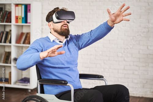 Portrait of a disabled man sitting in a wheelchair and using a VR headset