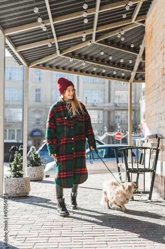 Quadro em tela Girl walks with a dog Tibetan spaniel on a street