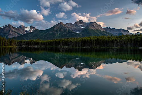 MOUNTAINS AND CLOUDS REFLECT OFF THE SURFACE OF HERBERT LAKE AT DUSK - BANFF NP