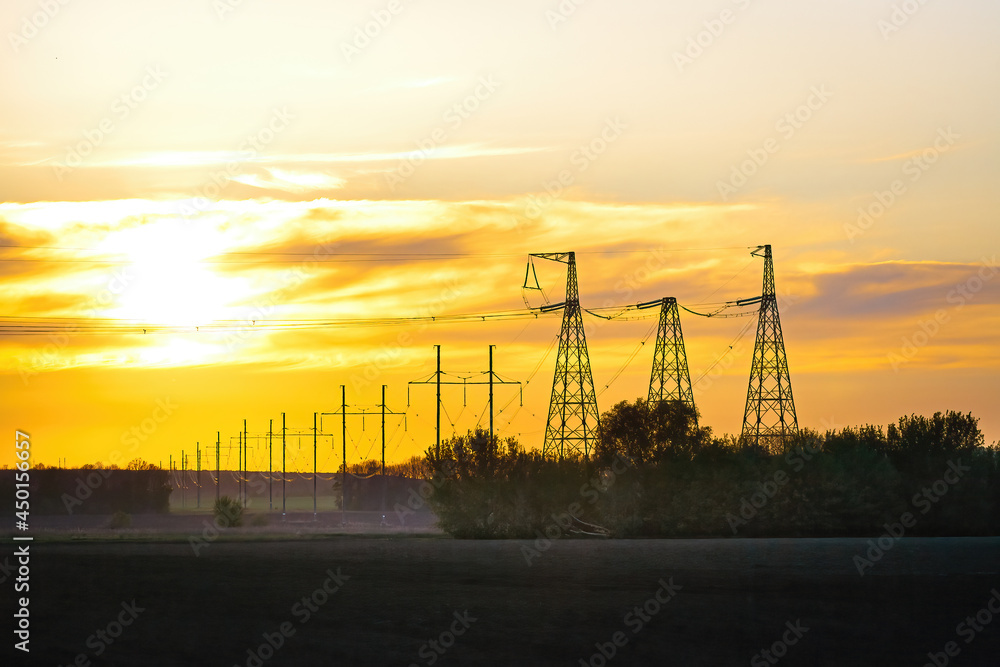 Transmission tower at sunset. Electric transmission station with metal poles and electrical wires.