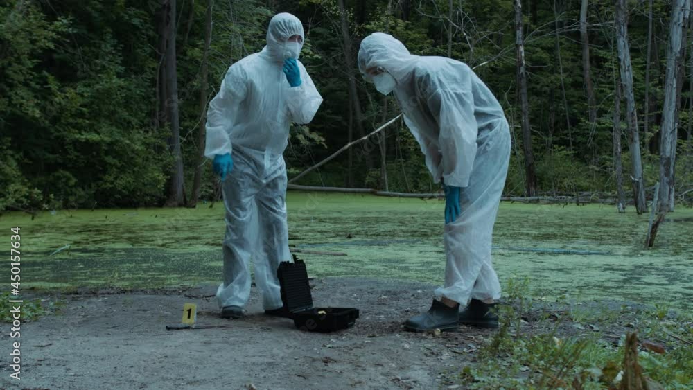 Criminalists working with knife at crime scene, territory closed with signal tape. Evidence from accident, murder. Investigating proof for forensic examination. Detective workers, medical examiners.