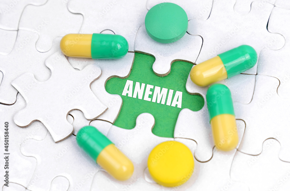 There are pills and vitamins on the white puzzles. Inside on a green background the inscription - ANEMIA There are pills and vitamins on the white puzzles. Inside on a green background the inscription - ANEMIA
