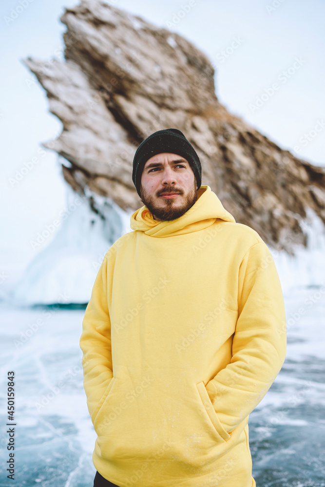 handsome man wearing yellow swetshirt and hat on a lake called baikal located in siberia in winter. Winter cold tourism handsome man wearing yellow swetshirt and hat on a lake called baikal located in siberia in winter. Winter cold tourism