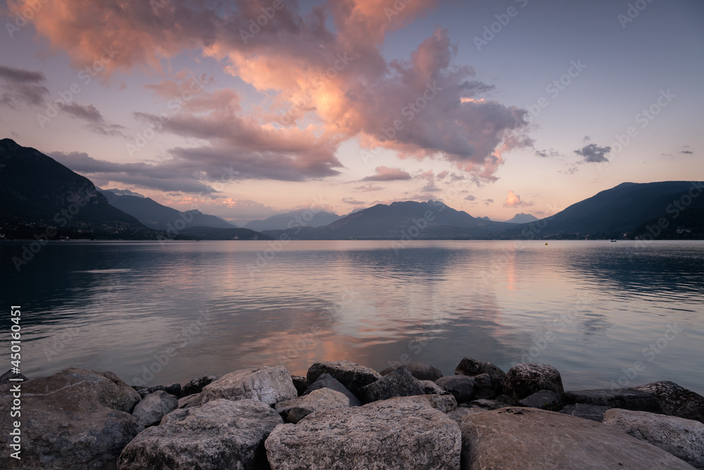 Natural landscape of Lake Annecy with colorful clouds at sunrise and Alps mountains in the background, Annecy, France