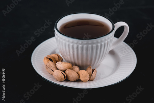 Pistachios in a white plate on a black background