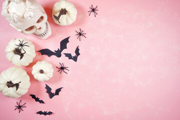 Modern pink Halloween theme flatly background with white skull, pumpkins, lollipops and bats. Negative copy space.
