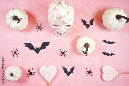 Modern pink Halloween theme flatly background with white skull, pumpkins, lollipops and bats.