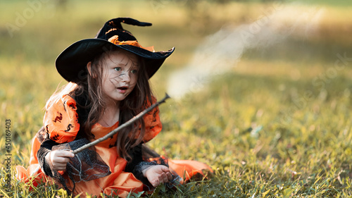 Little witch girl conjures magic wand on Halloween. © TISHKOVA