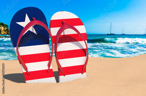 Flip flops with Liberian flag on the beach. Liberia resorts, vacation, tours, travel packages concept. 3D rendering