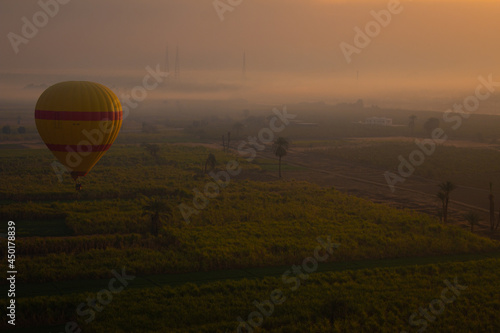 A hot air balloon at sunrise in the thick morning fog by the Nile, Luxor, Egypt