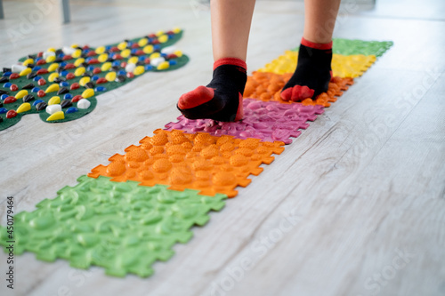 Fototapeta Naklejka Na Ścianę i Meble -  Close up legs stepping on colorful orthopedic mats with different textures, foot massage, influence on nerve endings, rehabilitation procedures