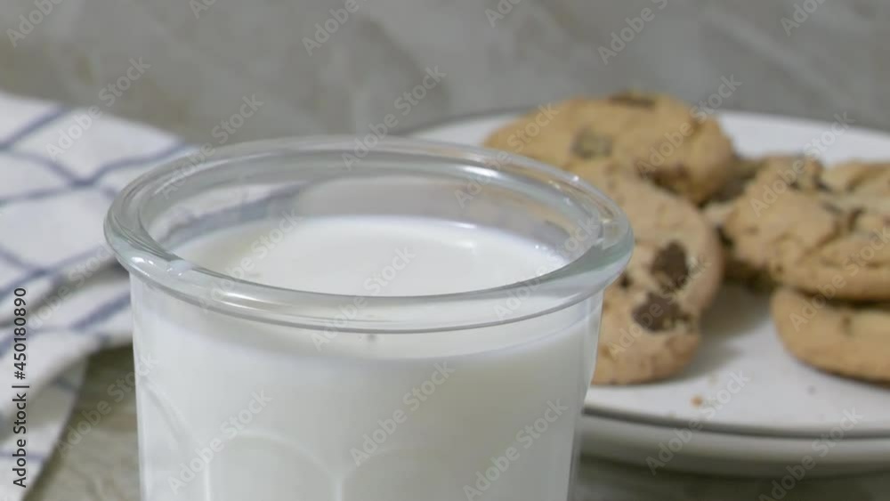Dunking a chocolate chip cookie into a glass of milk
