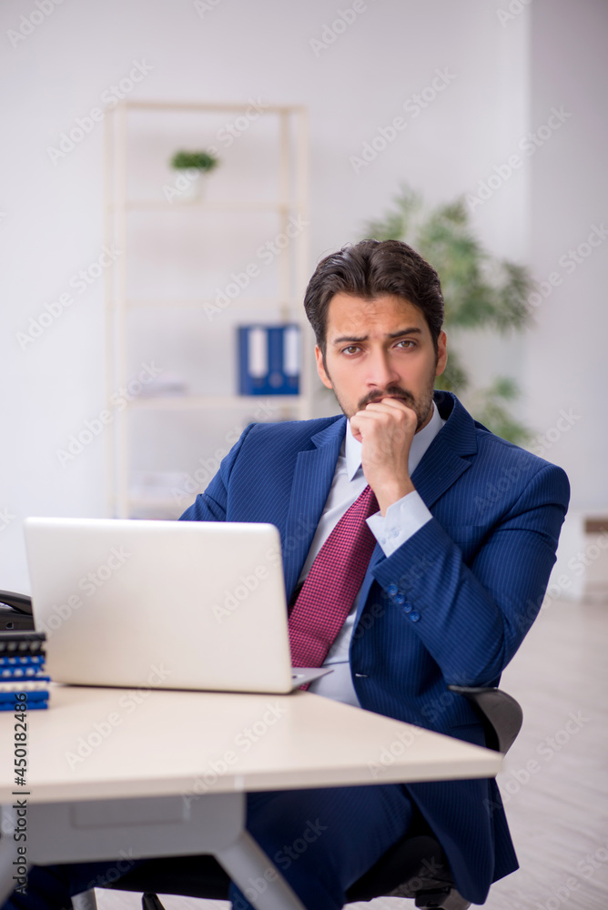 Young male employee unhappy with excessive work in the office Young male employee unhappy with excessive work in the office