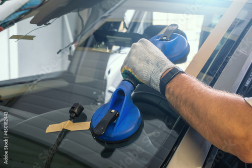 Valokuva Mechanic changes windscreen or windshield on car close up.